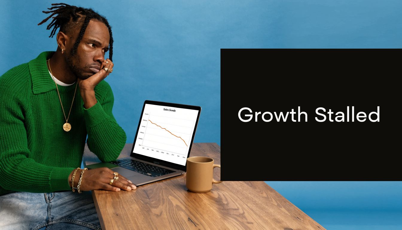 A concerned young man in a green sweater looks at a declining sales graph on a laptop screen.
